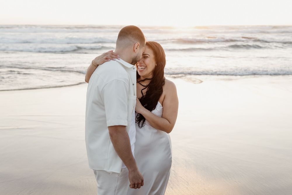 A couple shares romantic moments together on a sandy beach at sunset.