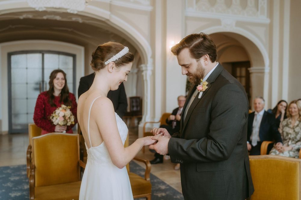 A couple exchanges rings during their traditional church wedding ceremony as guests look on from wooden pews.