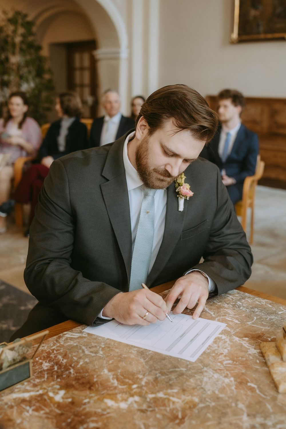 Wedding guest signing official documents on a marble table during ceremony.