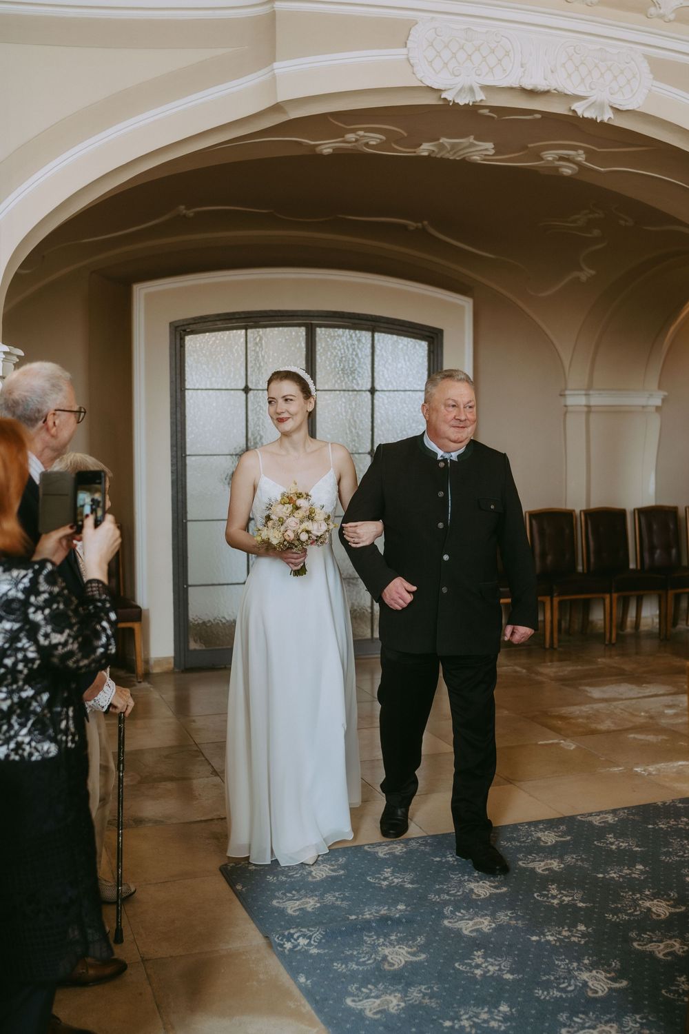 A series of photos showing a bride and older gentleman walking through an elegant ballroom with ornate architecture.
