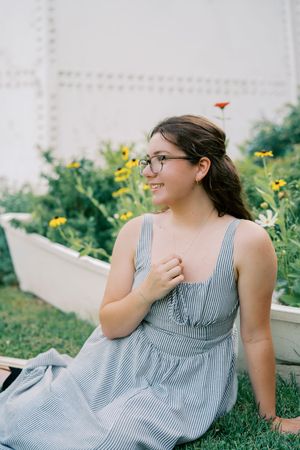 A striped gray sundress is featured in an outdoor garden photoshoot on grass.