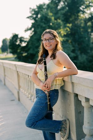 Casual outdoor photoshoot with someone leaning on a concrete railing in summer attire.