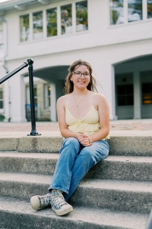 Relaxed poses on concrete steps outside a white building with windows.