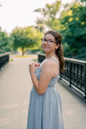 Outdoor photoshoot on a bridge wearing a striped blue dress.