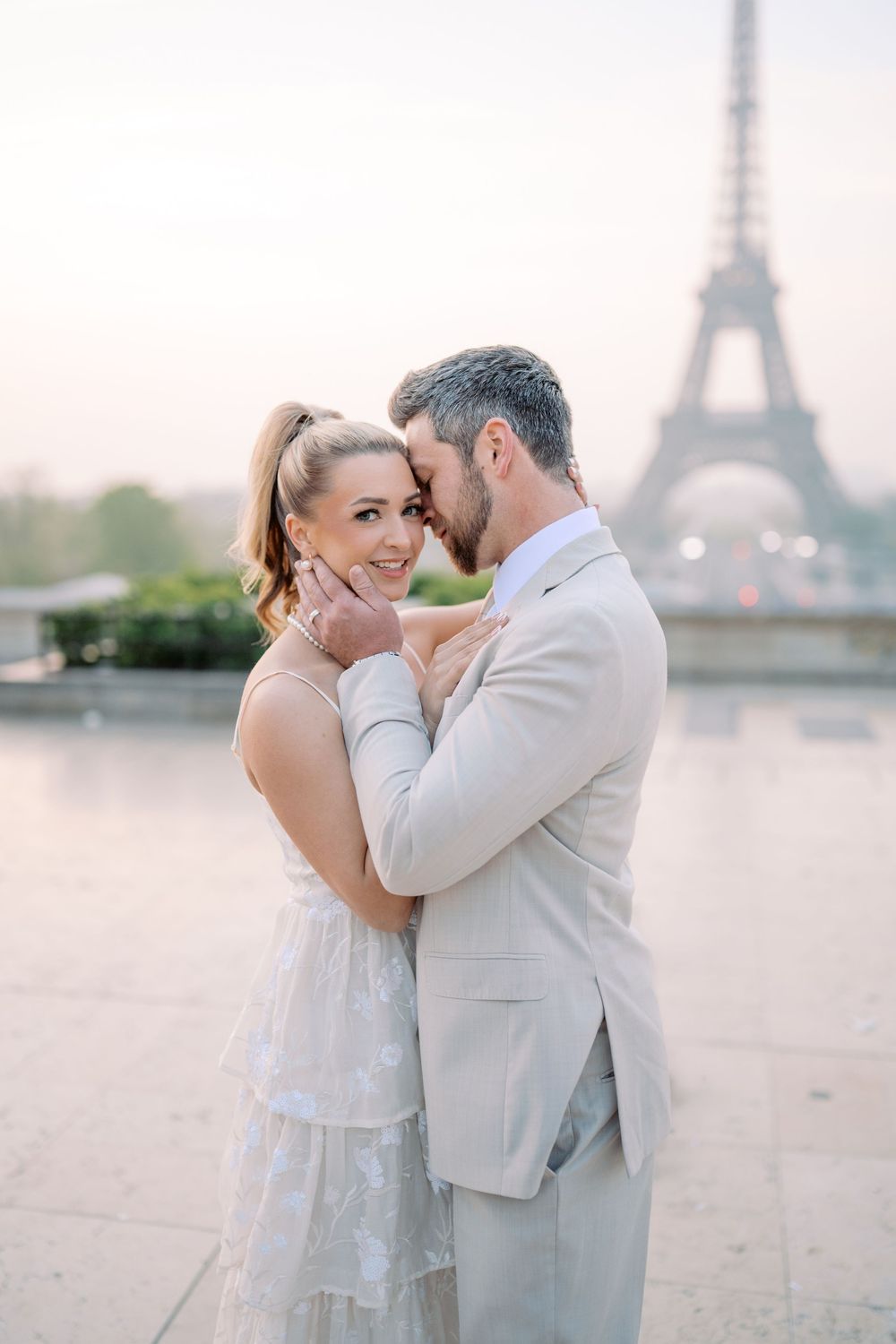 A romantic couple embraces in front of the Eiffel Tower during a dreamy sunrise photoshoot in Paris.