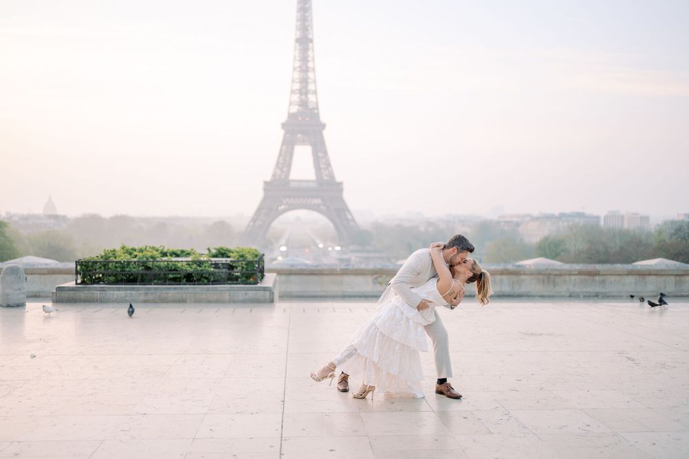 A romantic wedding photoshoot with the iconic Eiffel Tower in Paris creating a dreamy backdrop in the morning mist.