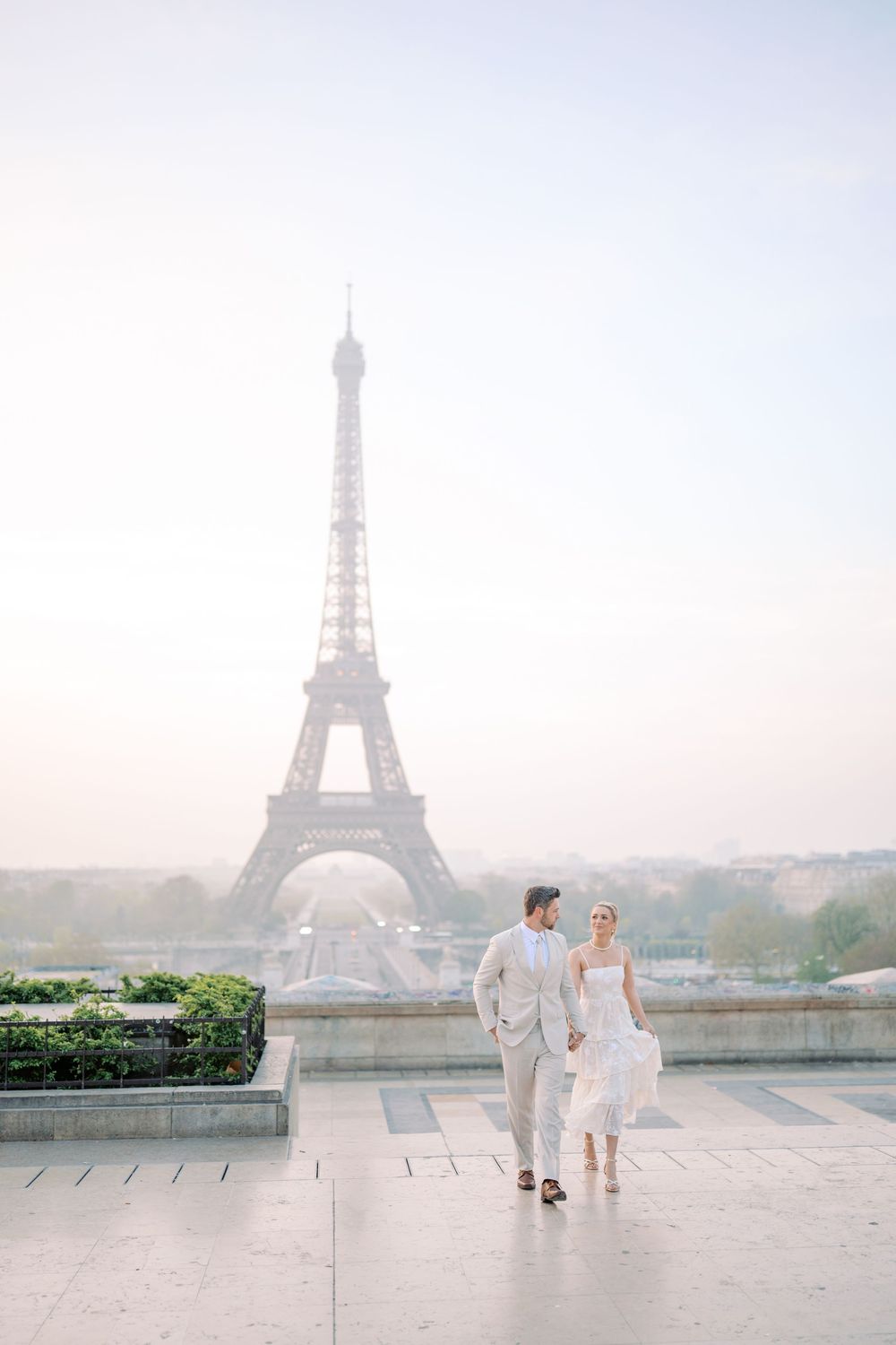 A romantic wedding photo sequence showing a couple in white against the misty Eiffel Tower backdrop in Paris.