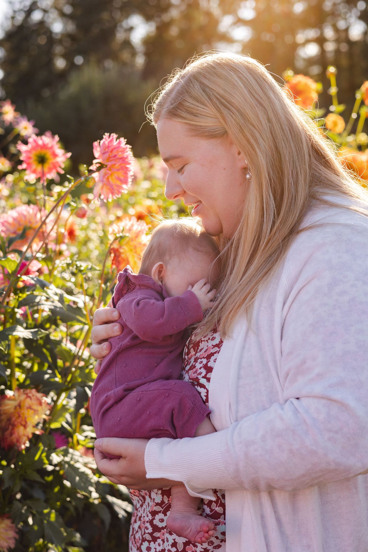 Couple shares tender moment surrounded by vibrant pink and yellow flowers in a garden setting during golden hour.