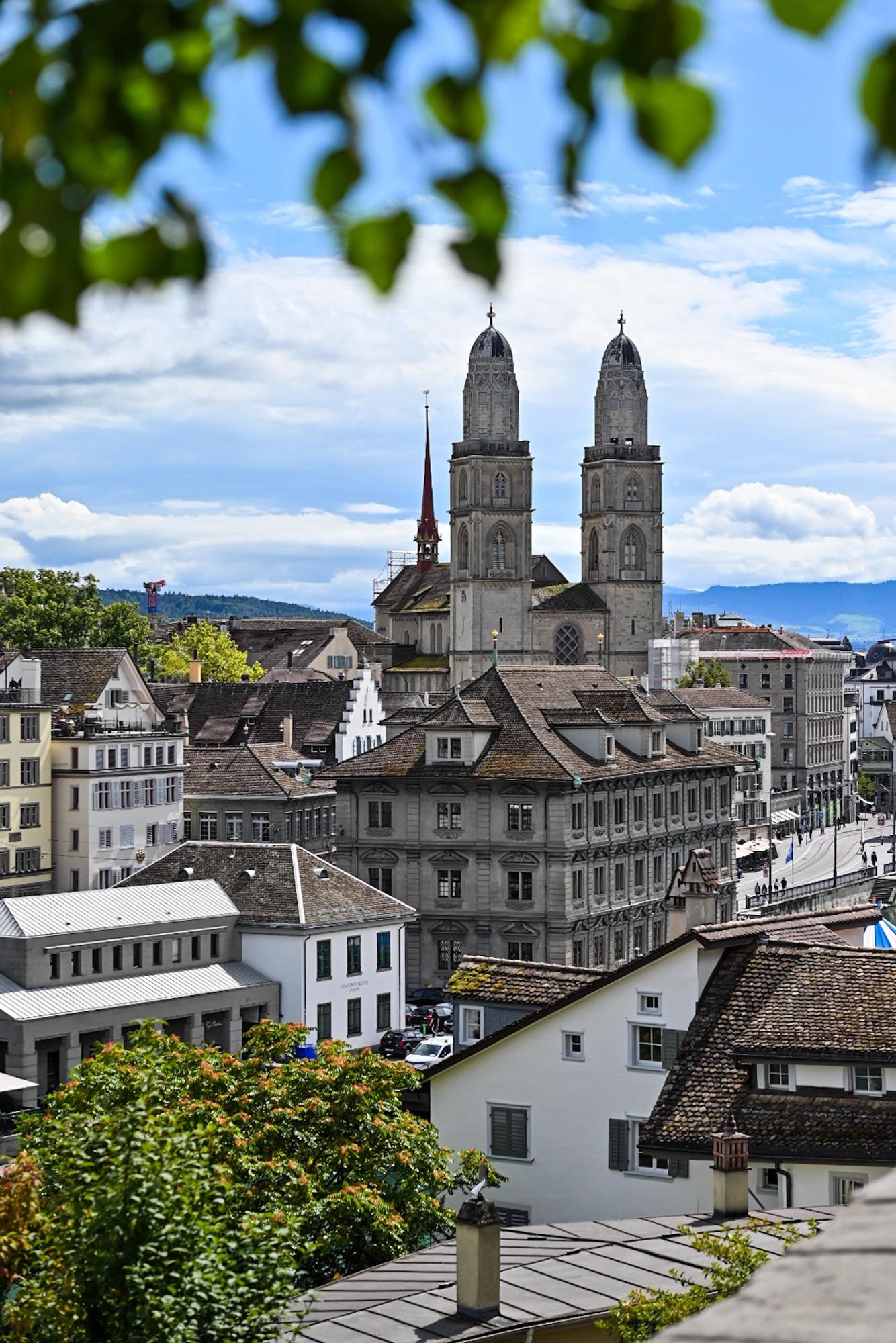 Panoramic view of historic Zurich cityscape with Grossmunster cathedral towers and traditional Swiss architecture.