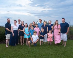 A series of five family photos taken in a grassy field with mountains and sky in the background.