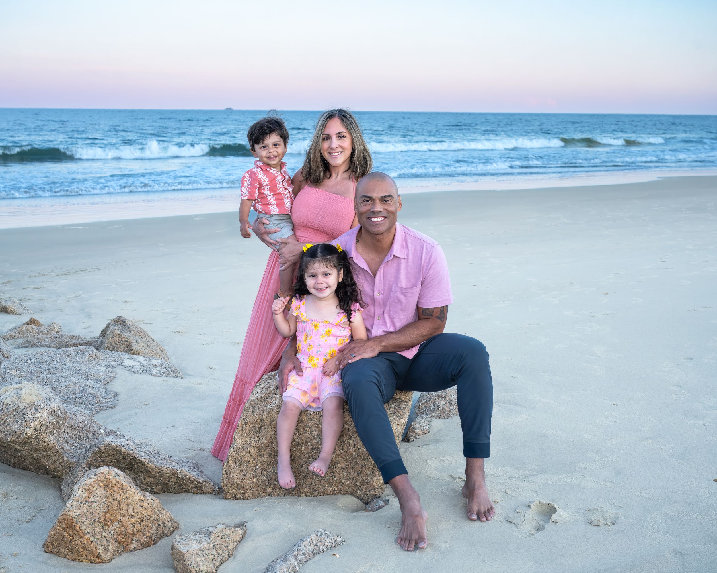 Family enjoying quality time together at the beach during sunset while sitting on seaweed washed ashore.