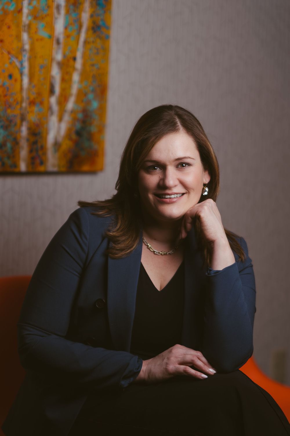 Business portrait session with orange abstract art backdrop in studio setting.