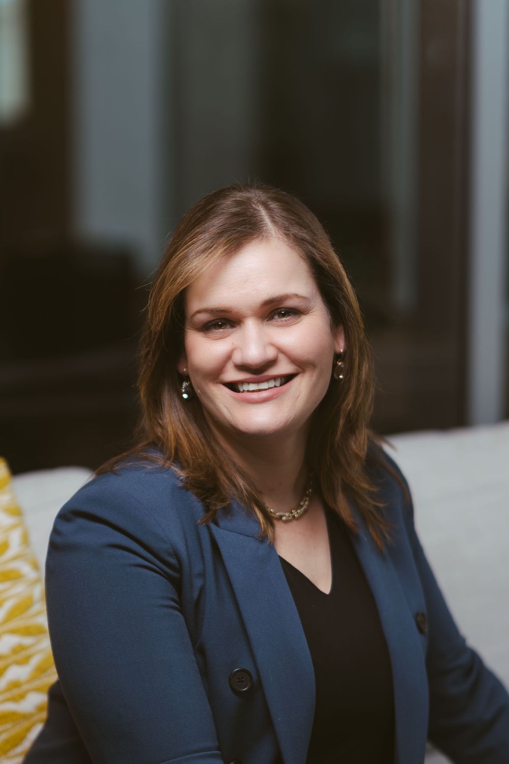 Business portrait in navy blazer against modern office background.