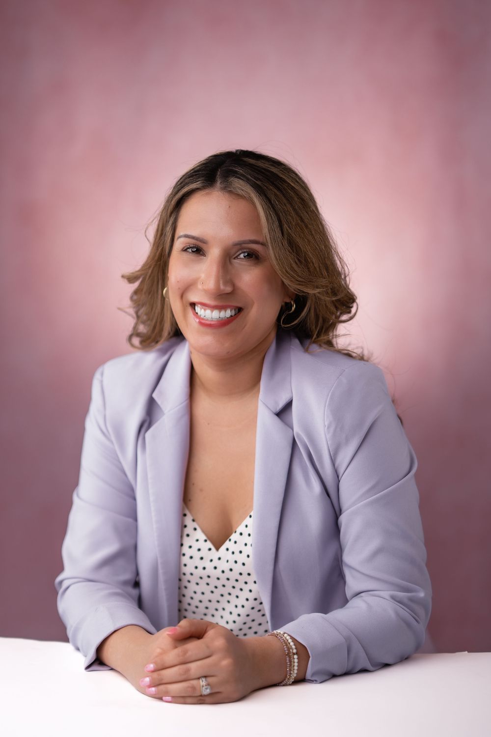 Corporate headshots of professional in lilac blazer against soft pink background.