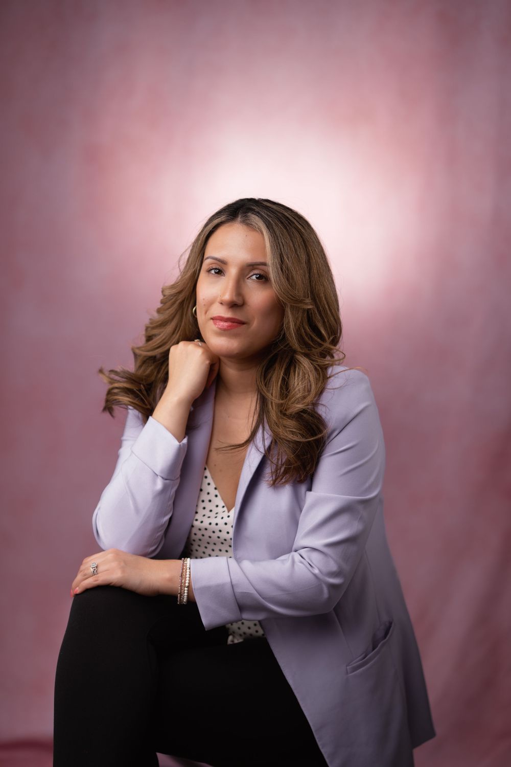 Studio portraits featuring woman in purple blazer with styled hair against pink backdrop.