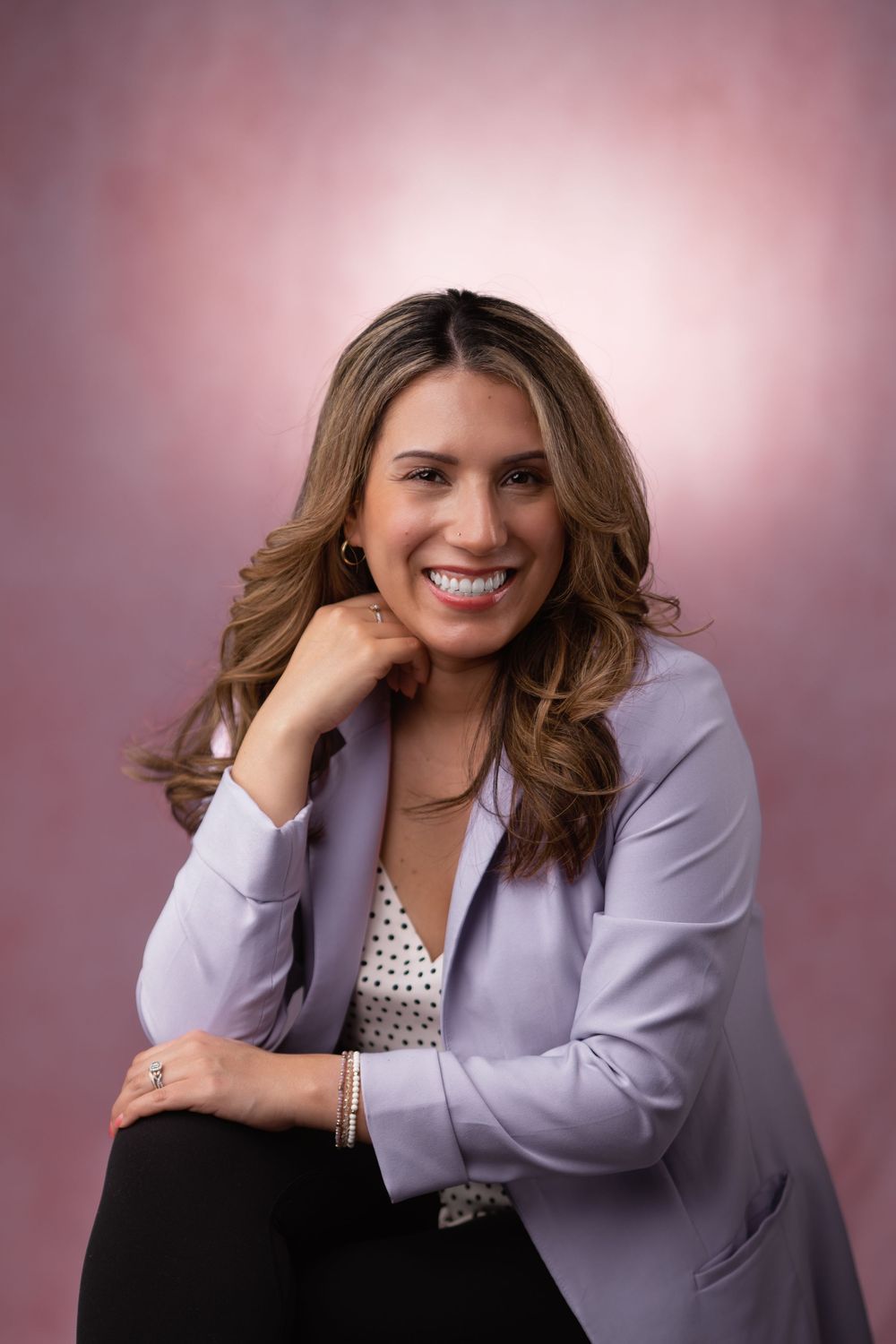 Professional photography session with woman in business attire against pink studio background.