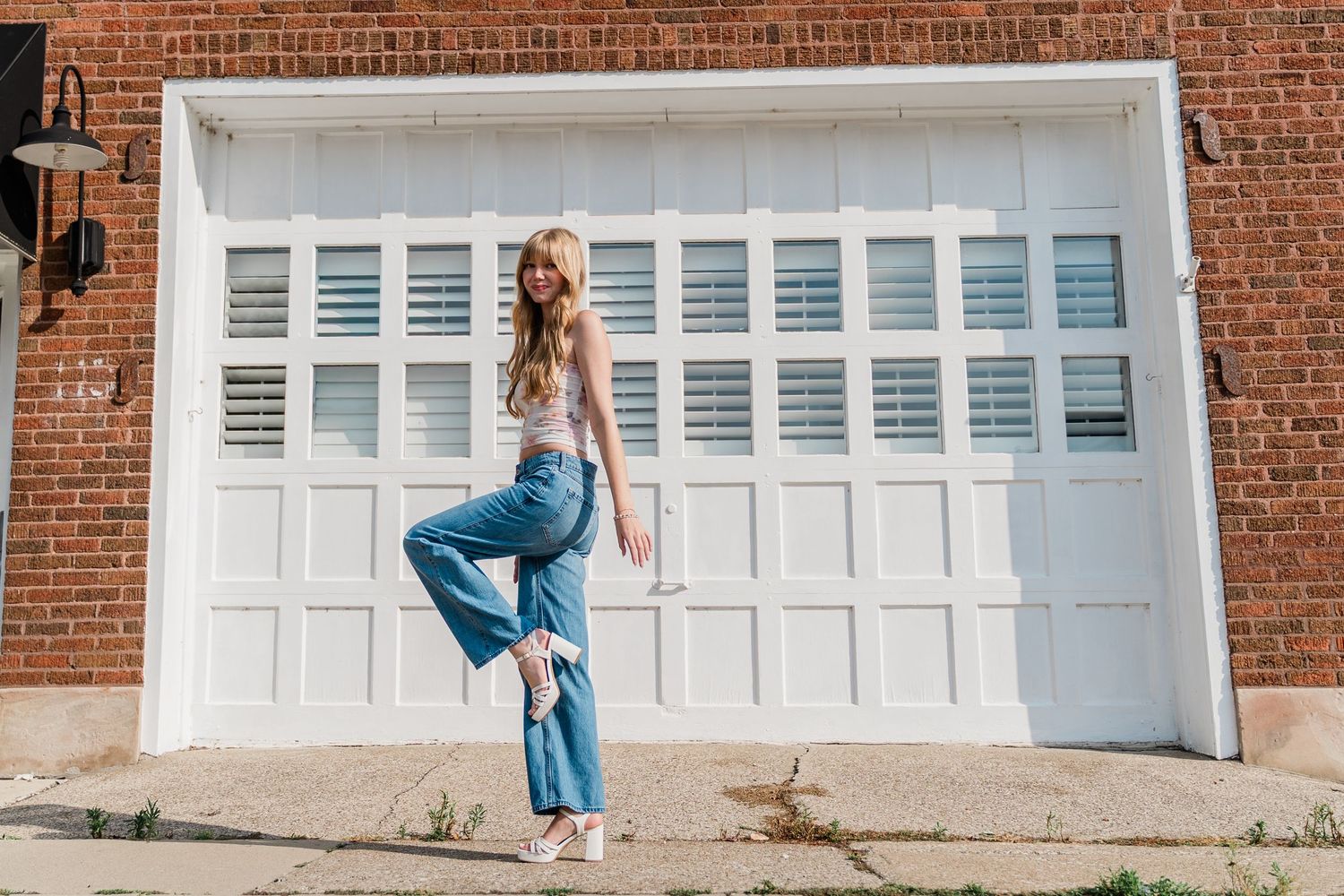 Casual senior portrait of Perrysburg High School student in blue jeans and white top posing playfully in Downtown Perrysburg