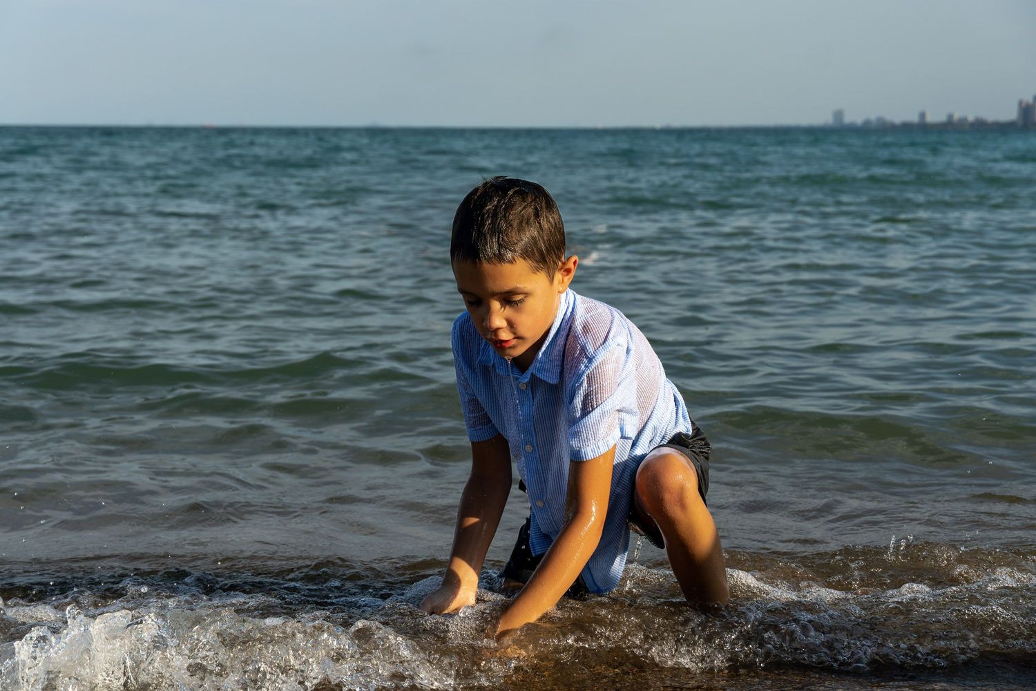 A young boy playing in the waves at the beach.