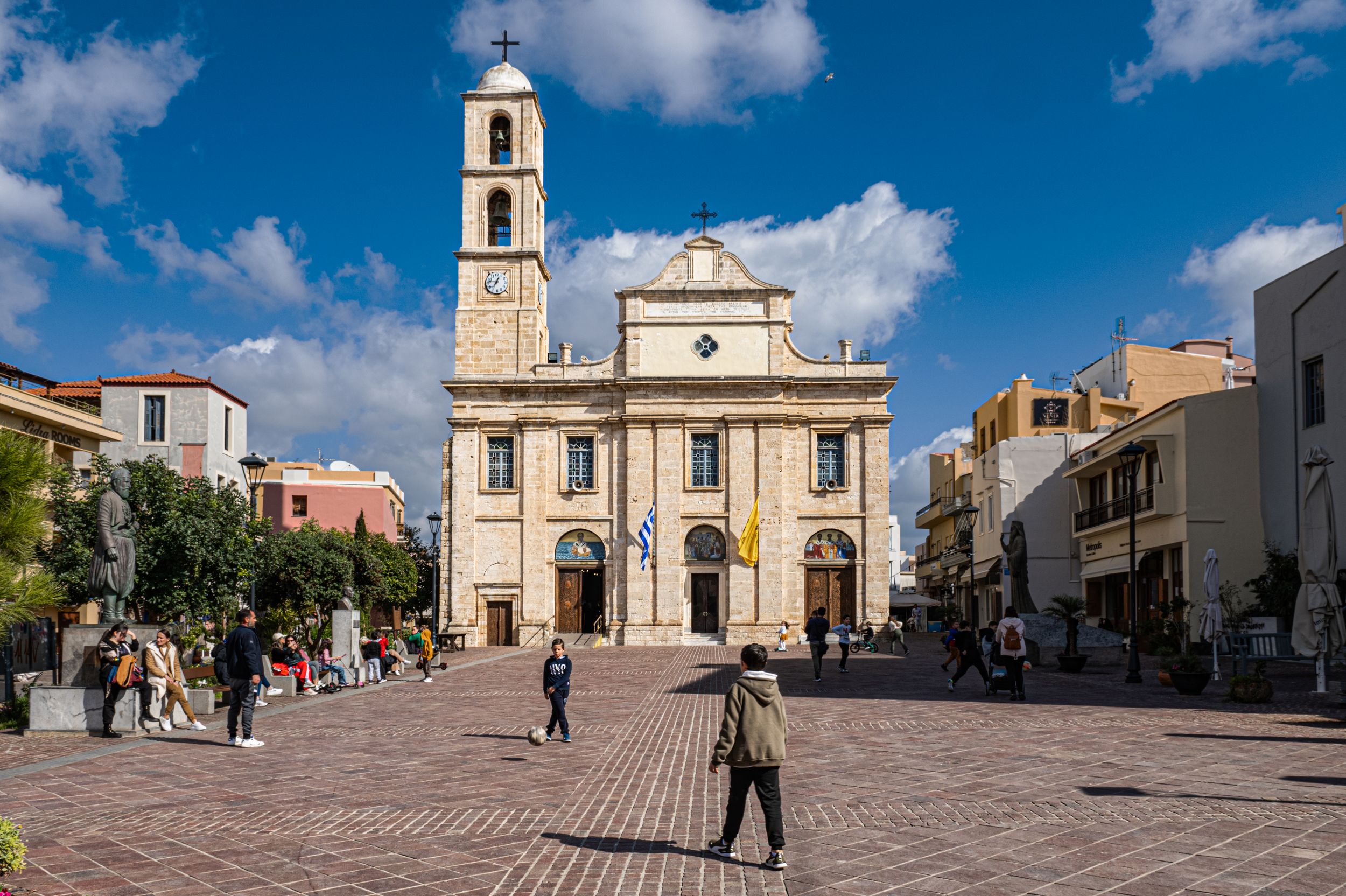 A panoramic view of a historic Italian town square with traditional architecture and a church under bright blue skies.