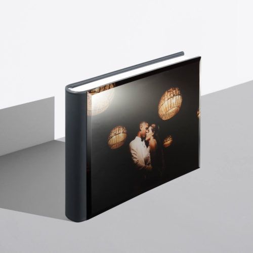 Custom hardcover photo album featuring a romantic couple kissing, displayed at an angle on a gray surface.