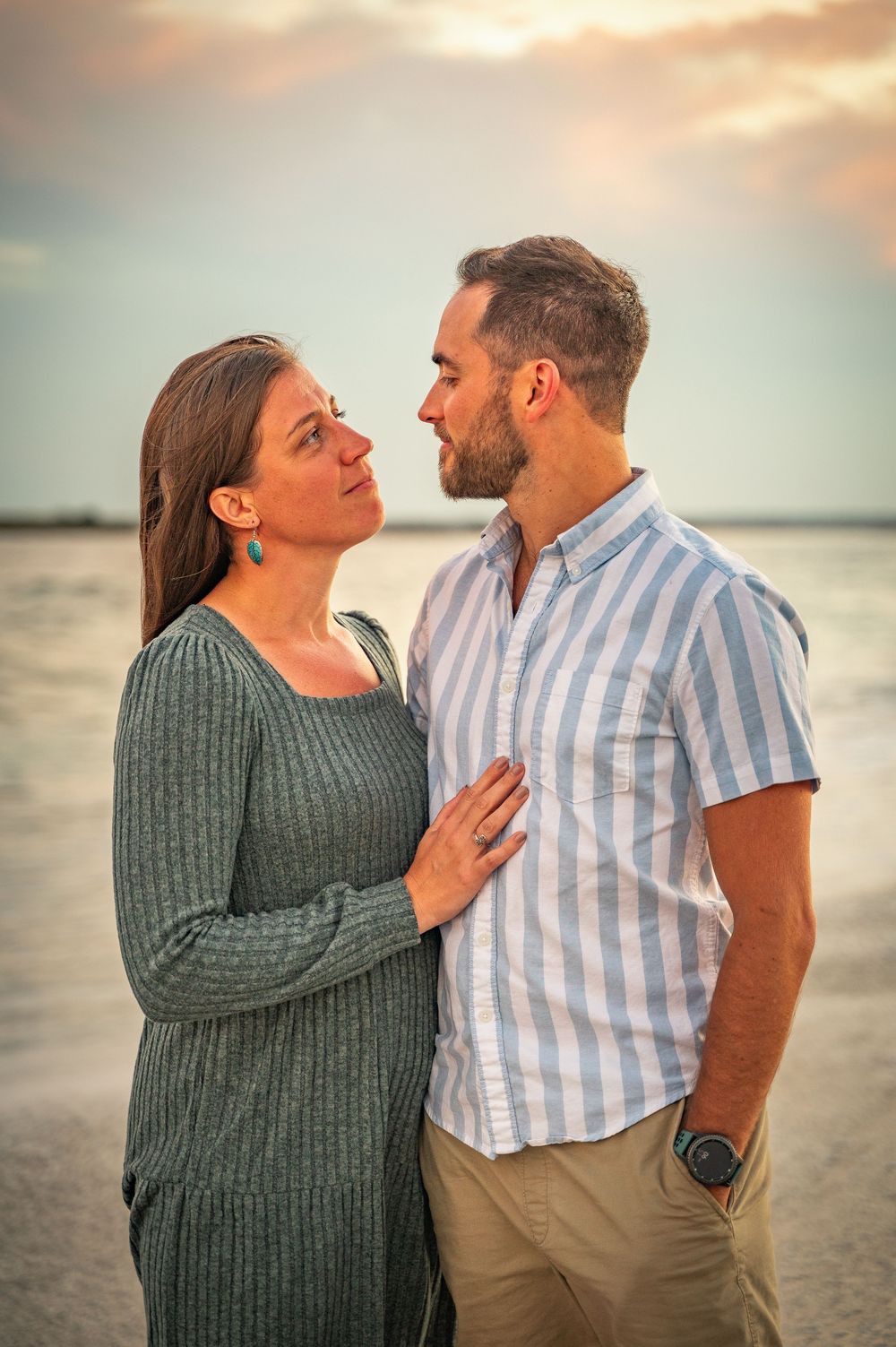 Romantic couple shares tender moments during sunset photoshoot at the beach.