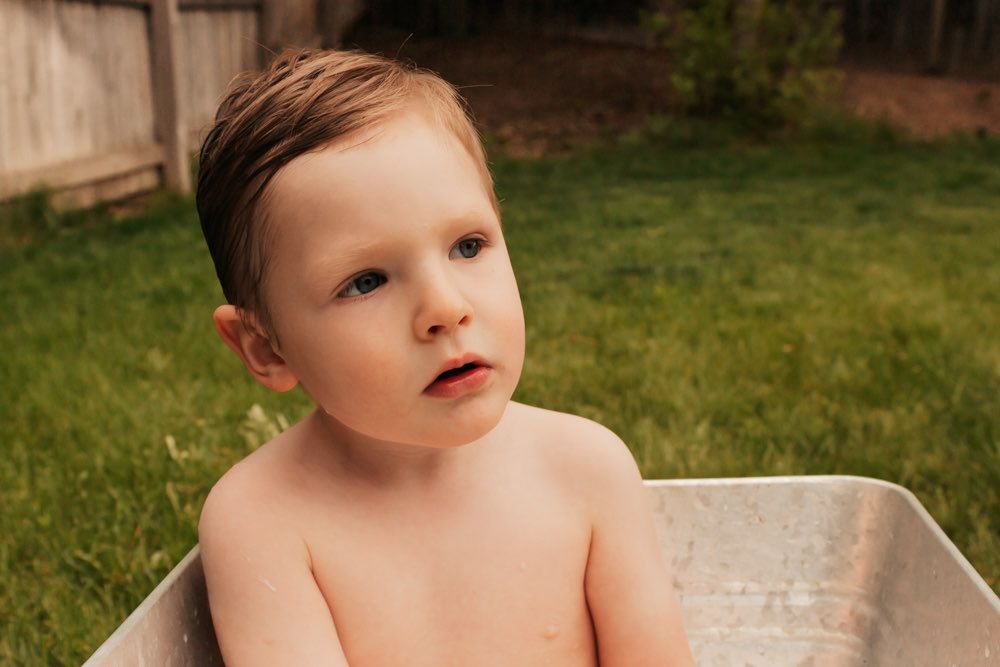 Toddler sitting in a vintage metal tub outdoors during in-home milestone session | Broomfield Family Photographer