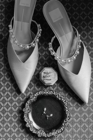 Elegant white pointed-toe shoes with rhinestone embellishments arranged in a row against a patterned background.