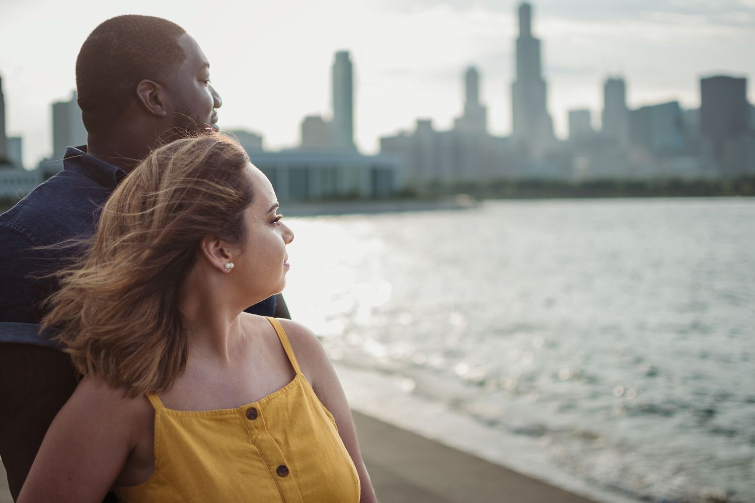 A couple stands by the waterfront looking at the Chicago skyline on a sunny afternoon.