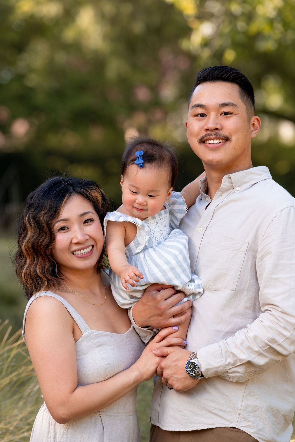 A family in coordinating white outfits poses together outdoors during a golden hour photo session.