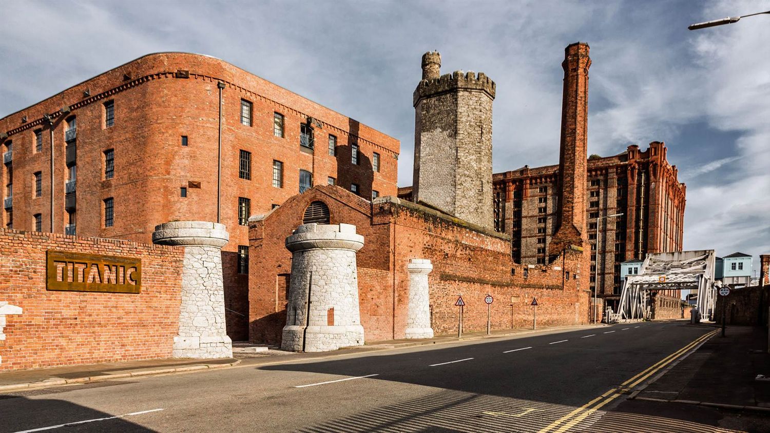 Historic red brick buildings and industrial architecture line an urban street under dramatic cloudy skies.
