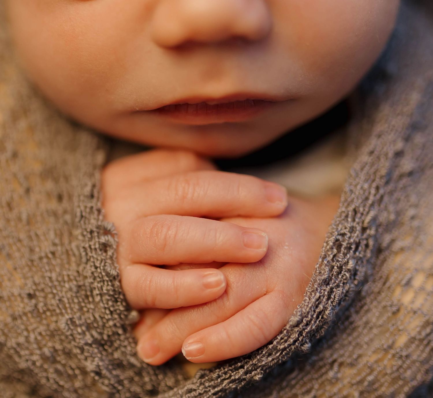 Close-up progression of tiny baby fingers grasping a textured gray blanket or fabric in multiple sequential frames.