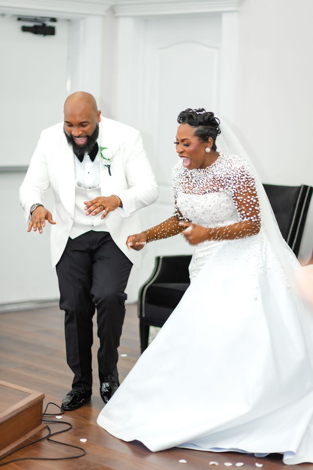 A couple shares joyful moments together in a white room during their wedding photoshoot.