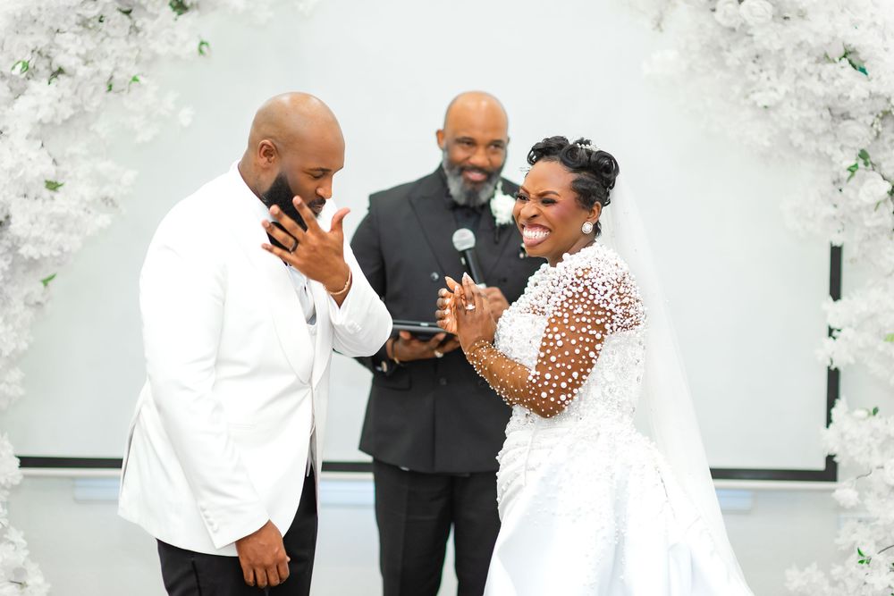 Wedding couple shares a joyful moment together during their celebration surrounded by white floral decorations.