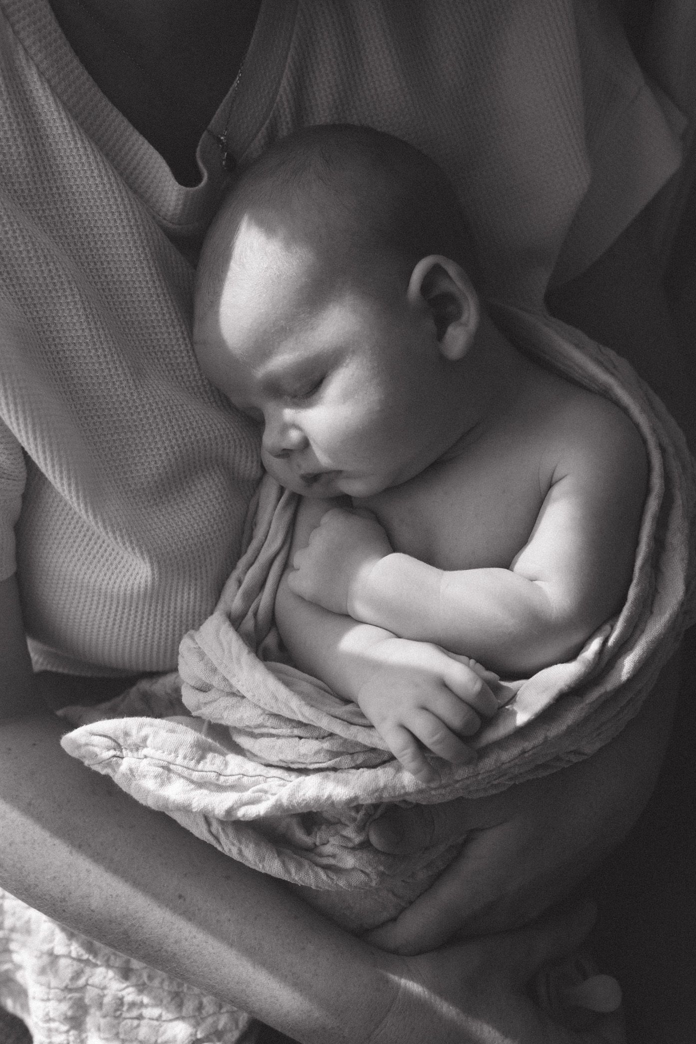 Black and white series showing peaceful sleeping baby wrapped in textured blanket.