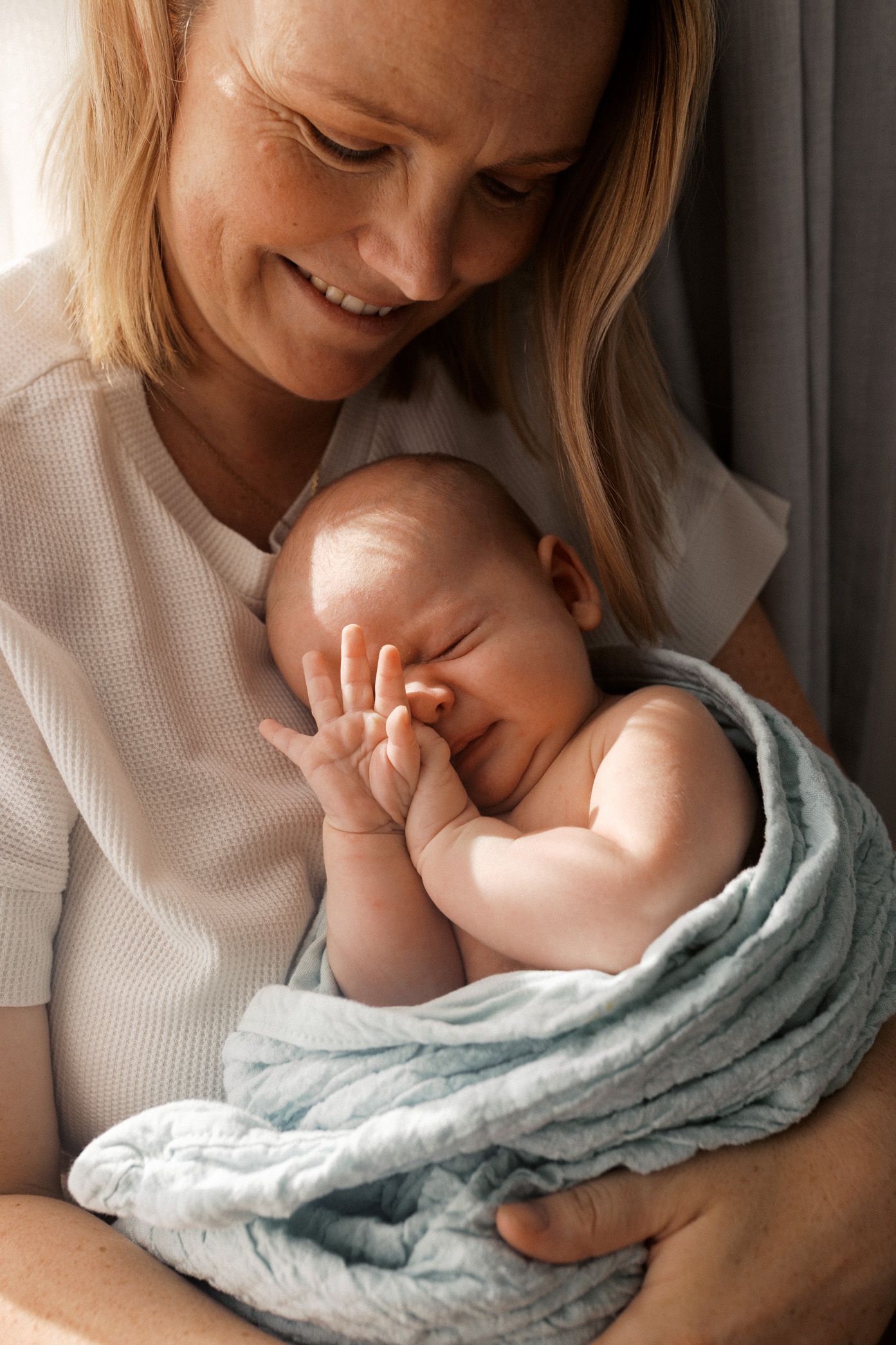 A tender moment captured in a series of photos showing a parent holding a sleeping baby wrapped in a light blue blanket.