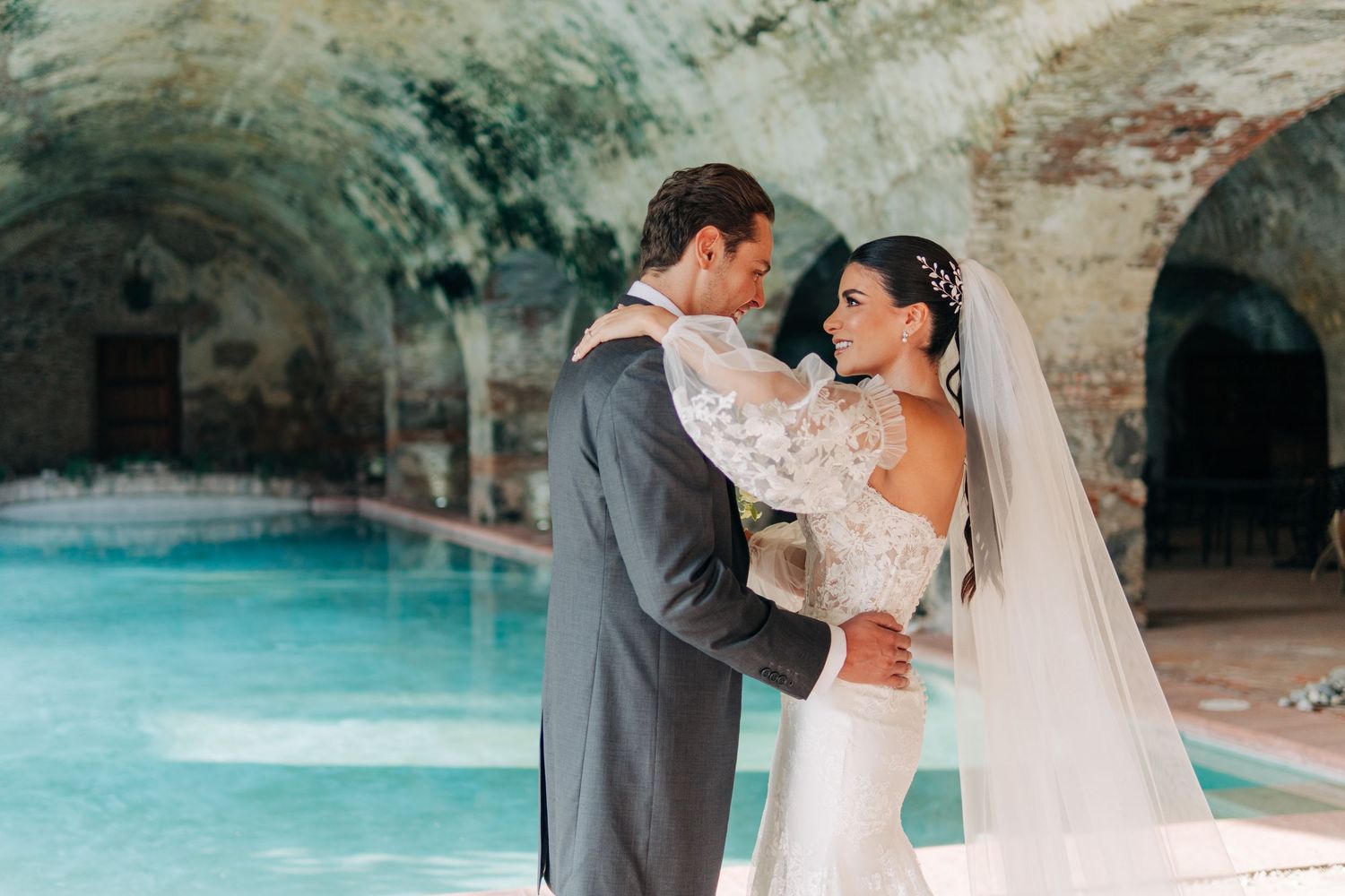 Newlyweds sharing an intimate moment by a turquoise pool at their wedding venue.