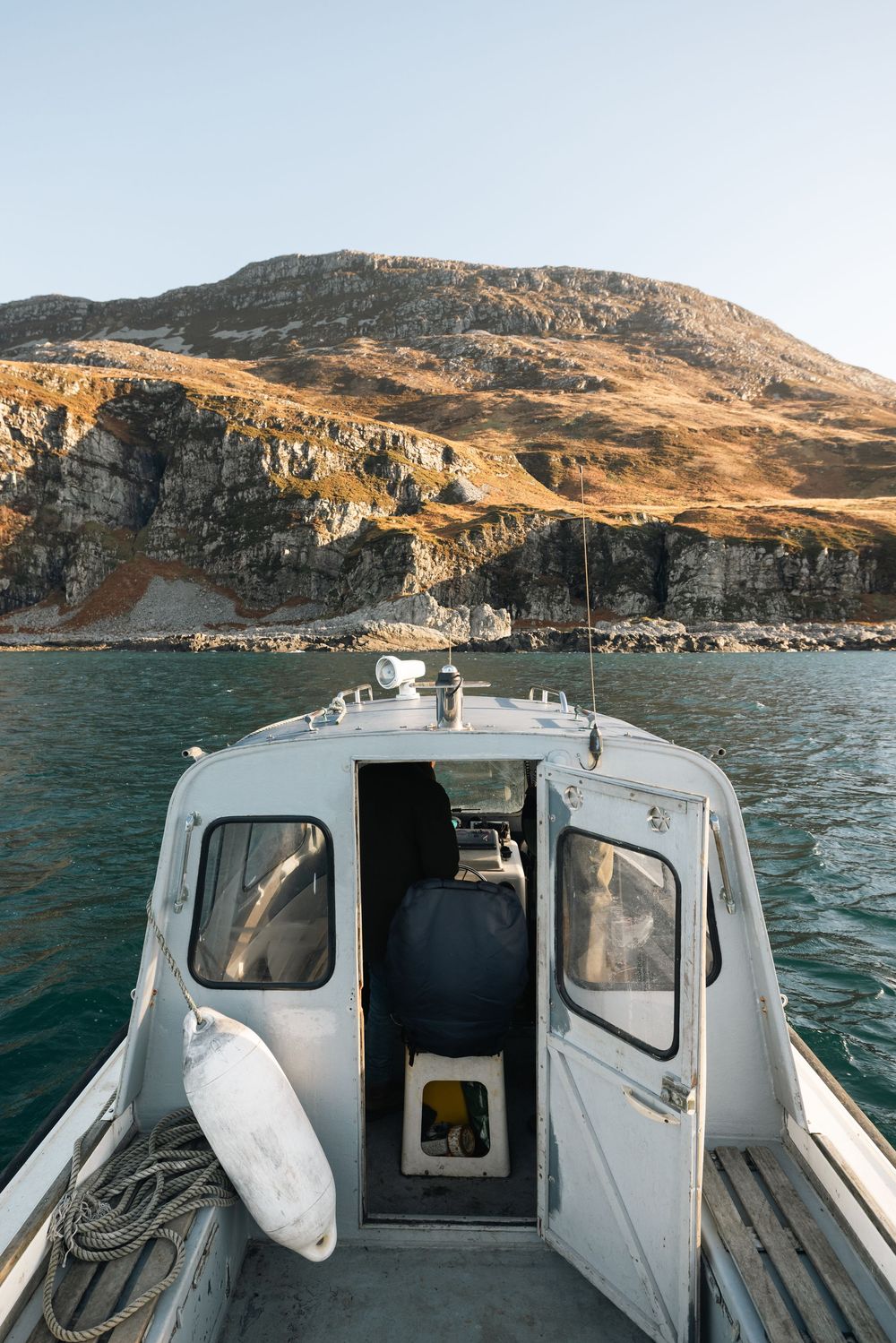 A series of photos showing a white boat cruising along rocky coastal cliffs during daytime.