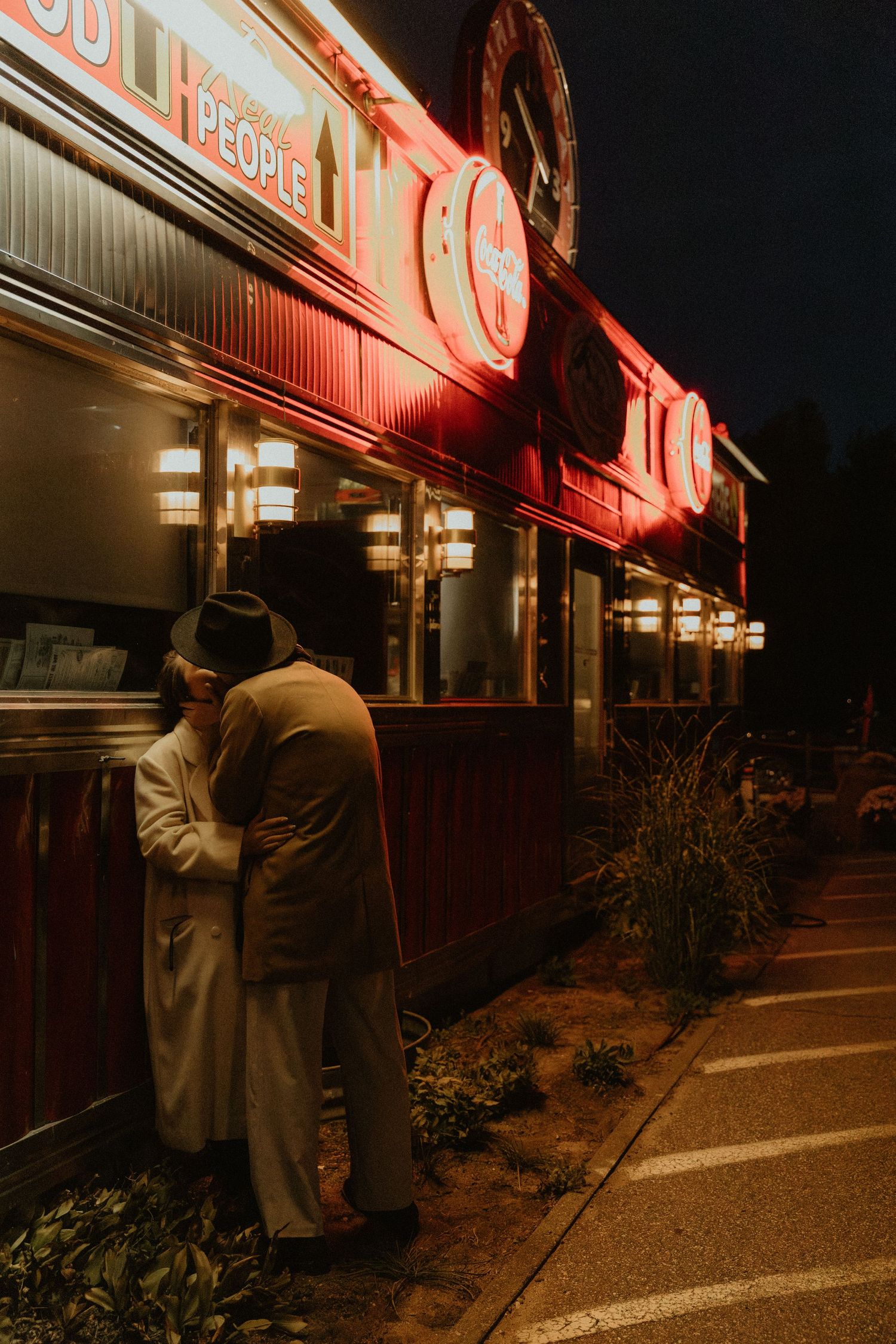 A couple stands in the glow of red neon lights at night creating a moody atmosphere.