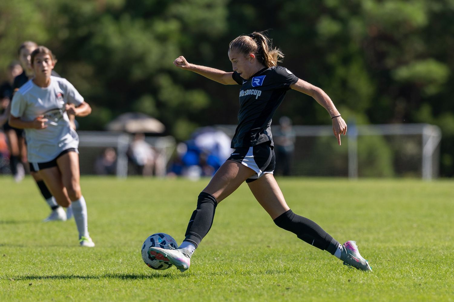 Athletes battle for possession during an intense soccer match on a green field.