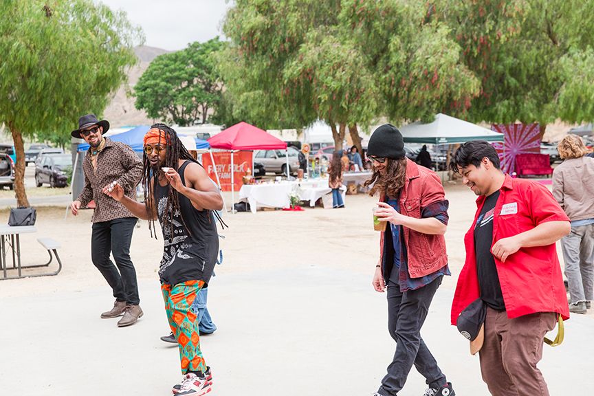 Musicians and performers dance and play instruments outdoors at a lively festival event.