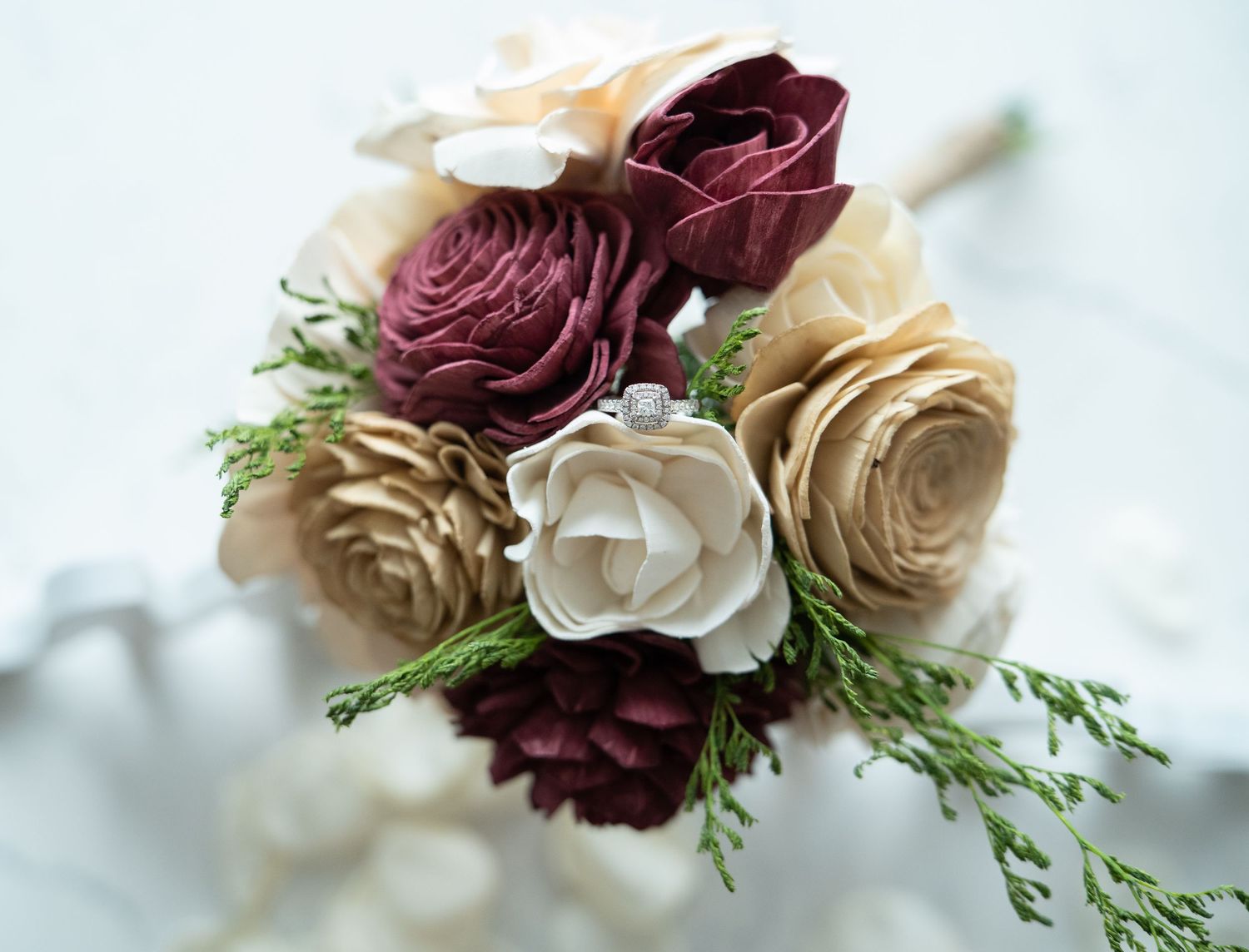 Handcrafted sola wood flower bouquet with burgundy, cream, and gold roses accented with green cedar foliage.
