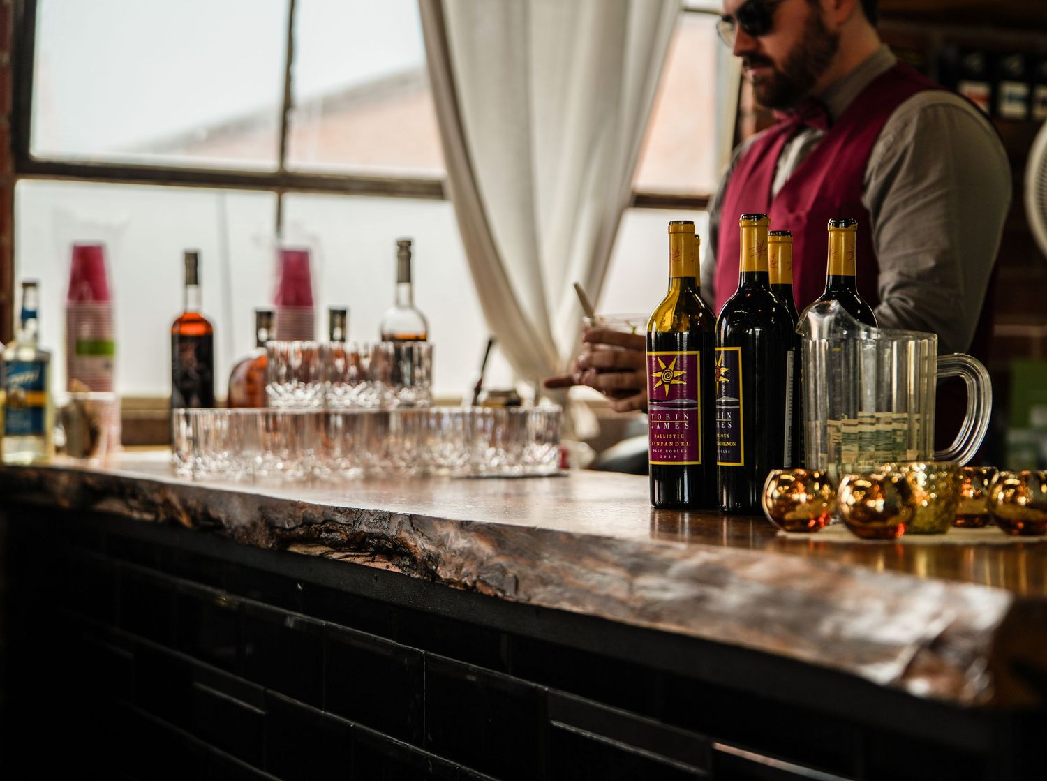 A bartender prepares drinks at an elegant bar with crystal glassware and decorative gold ornaments.