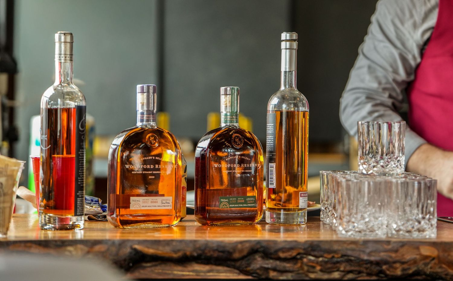 Four bottles of whiskey and bourbon lined up on a wooden bar counter at a wedding reception.