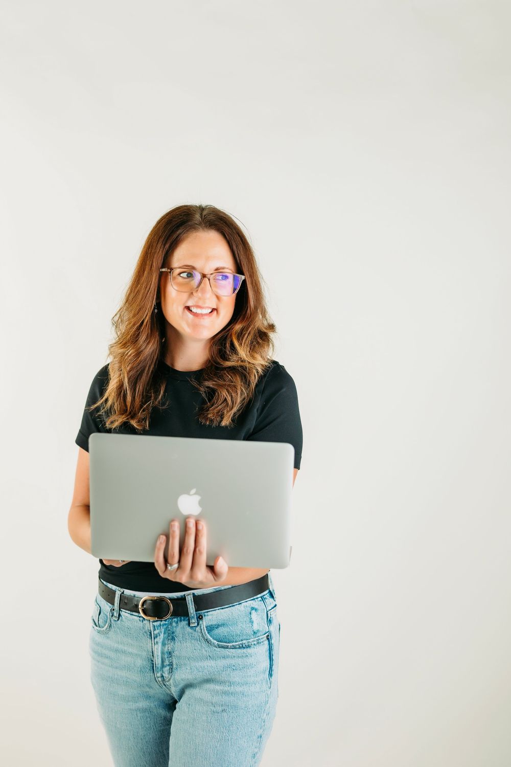 A series of photos showing someone in jeans holding and posing with a MacBook laptop against a white background.
