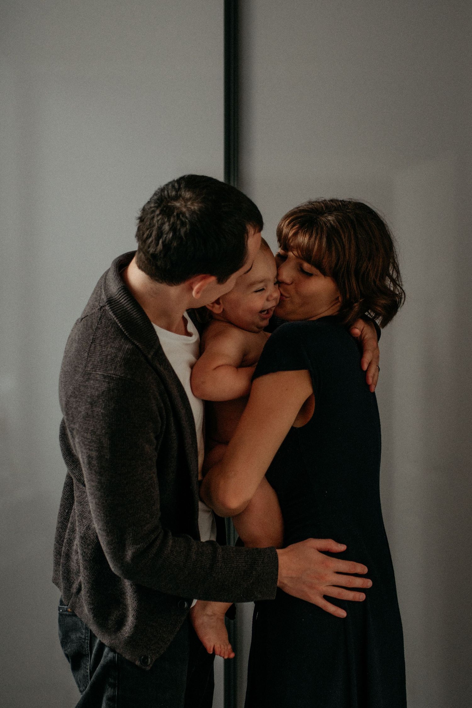 Parents embracing and kissing their baby during an intimate lifestyle family photography portrait in Gateshead