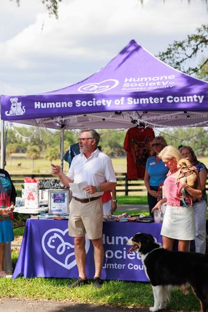 Humane Society of Sumter County purple tent display at outdoor adoption event.