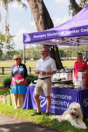 Humane Society booth setup at outdoor event with purple tent canopies and display tables.
