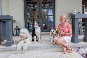 White fluffy dogs sitting with handlers on a porch outside a building.