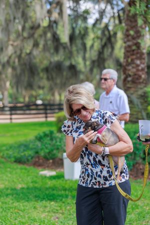 Person holding and cuddling small dog at outdoor Humane Society event.