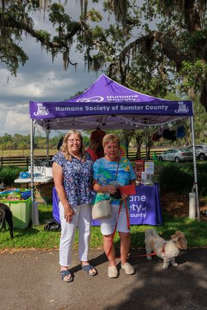 A Humane Society event tent set up outdoors with Spanish moss hanging from trees in the background.